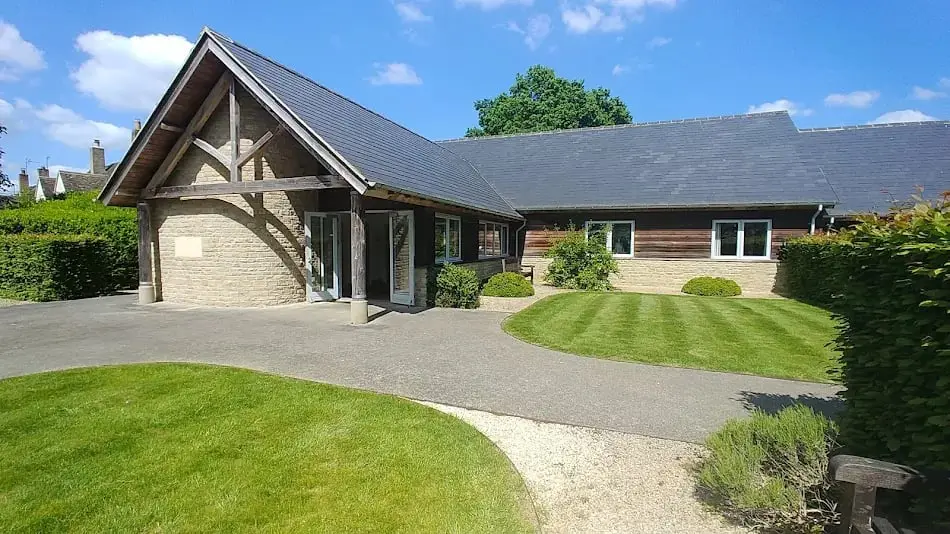 Freeland Village Hall, a modern single-storey hall with a timber-framed porch behind a striped lawn